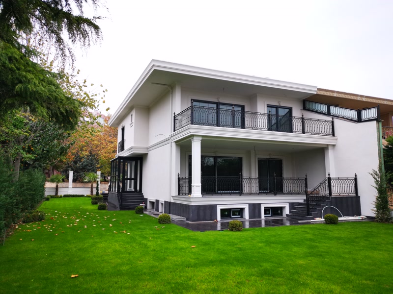 Geniş çim bahçeli iki katlı beyaz villa dış cephesinde poliüretan söve ve kare pilaster sütun uygulaması.