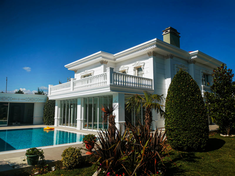 Geniş havuzlu beyaz villa dış cephesinde poliüretan söve, pilaster sütun ve balustrad balkon korkuluk uygulaması.