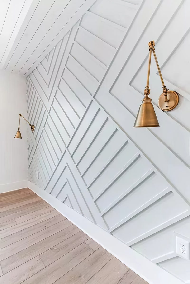 Poliüretan P851350 duvar çıtası ile hazırlanmış geometrik desenli salon duvarı ve pirinç aplik aydınlatma uygulaması