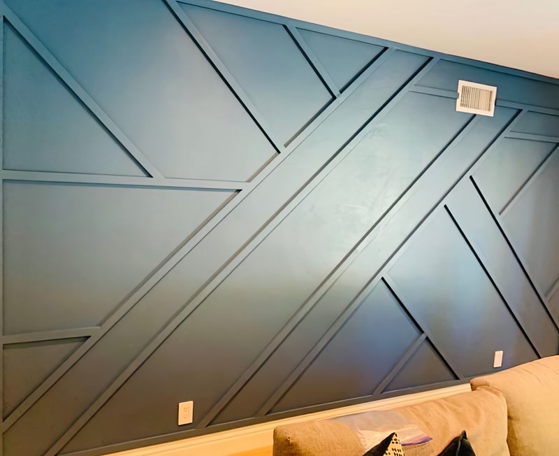 Koyu mavi renge boyanmış asimetrik geometrik poliüretan duvar çıtası uygulaması yapılan modern salon duvarı.