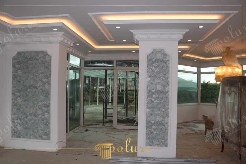 Geniş salon tavanında gizli ışıklı poliüretan kartonpiyer ve kolonda P82015 çıta çerçeve uygulaması