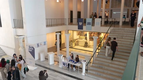 Atriyumun merdivenleri, sergi düzeni ve kalabalığı birlikte görülüyor