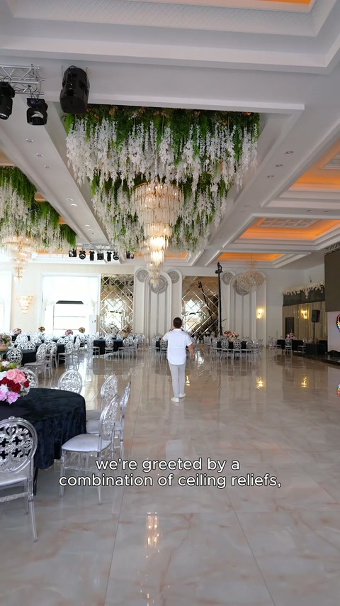 Geniş salon boyunca dekoratif sütunlar, tavan bordürleri ve avizeler uzanıyor