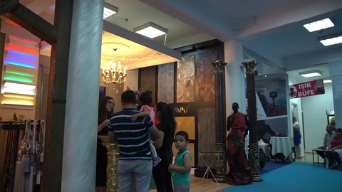 Dekoratif kolonlarla çevrelenen işyeri girişinde ziyaretçiler ürünleri inceliyor