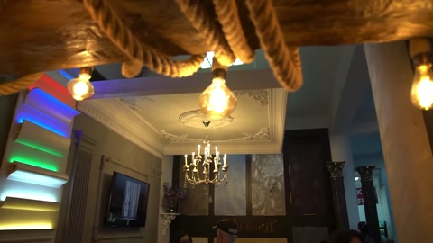 Renkli tavan katmanları, halatlı kirişler ve sarkıt aydınlatmalar görülüyor