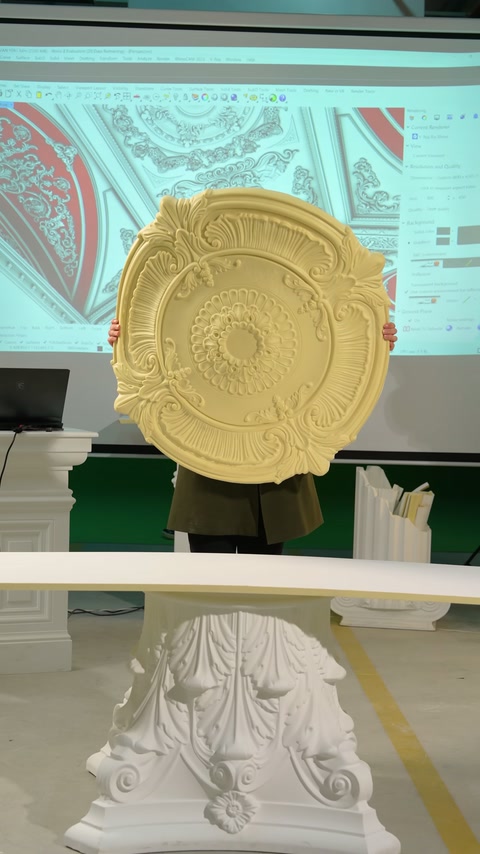 Dairesel kabartmalı tavan rozeti sunucu tarafından dikey biçimde tutuluyor