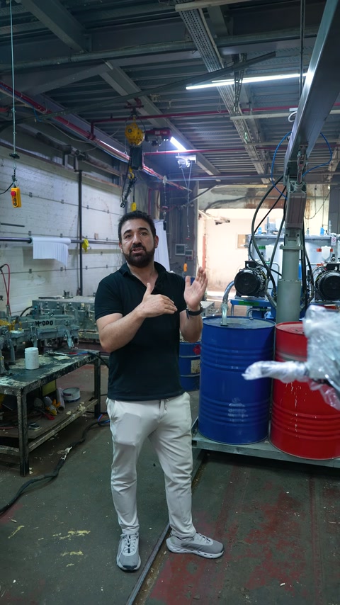 Sunucu, fabrika ekipmanlarının arasında elleriyle ürün detaylarını açıklıyor.