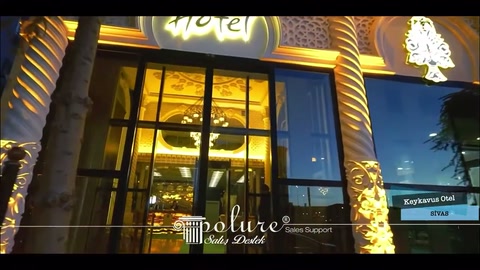 Aydınlatılmış otel kapısının çevresinde kabartmalı dikey süsler uzanıyor