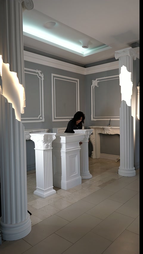 Üç beyaz dekoratif kaide salon zemininde yan yana düzenleniyor