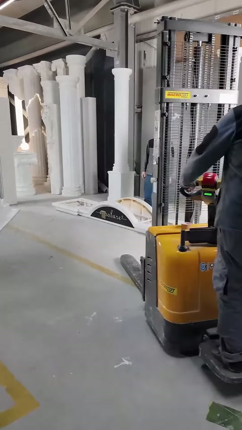 Operatör, kaldırma aracını beyaz sütunların yanına yaklaştırıyor.