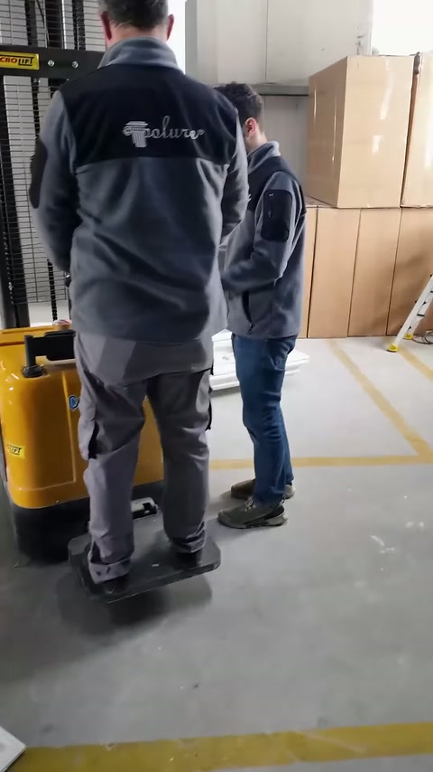 İki çalışan, kaldırma aracının yanında uygulama planını değerlendiriyor.