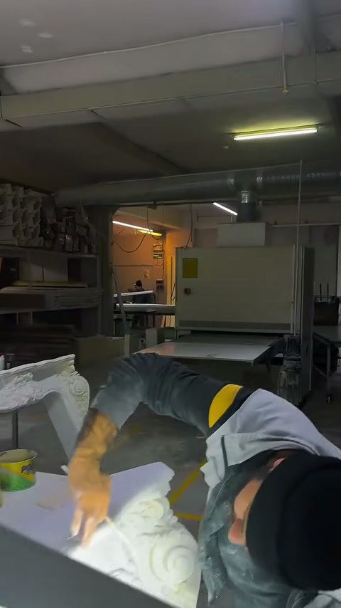 Çalışan, masadaki bezemeli sütun parçası üzerinde eğilerek çalışıyor.