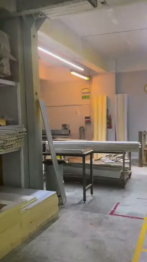 Üretim bölümünün geçiş alanında raflar ve çalışma masaları görülüyor.