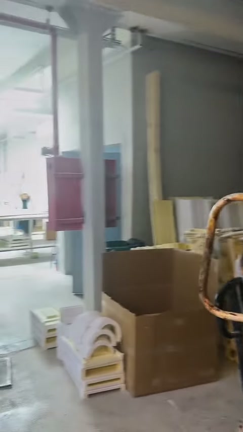 Kapı yanında kıvrımlı beyaz dekor parçaları kutularla birlikte istiflenmiş.