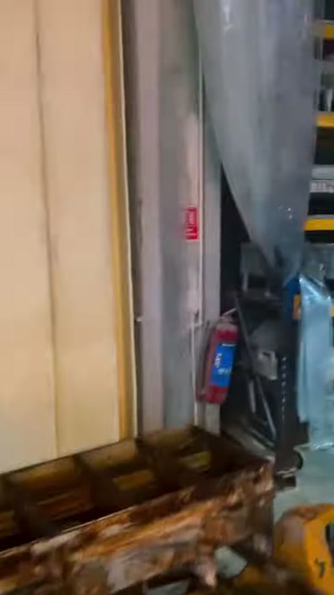 Çalışan, sarı panellerin önünde eğilerek parçalarla ilgileniyor.
