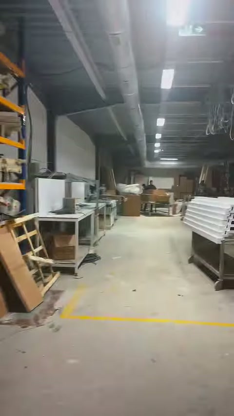 Üretim holünün orta koridorunda tezgâhlar, raflar ve malzemeler uzanıyor.