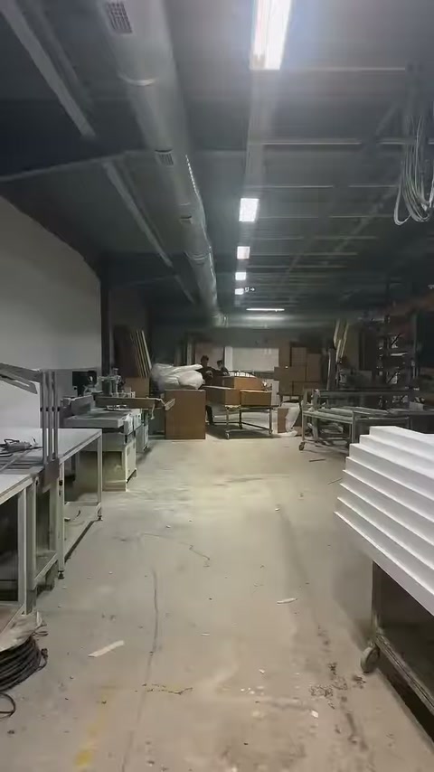 Geniş üretim alanında beyaz profiller ve paketleme kutuları sıralanıyor.