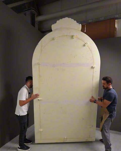 Ham poliüretan rölyef paneli atölyede iki kişi tarafından taşınıyor.