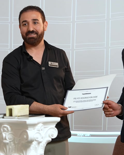 Konuşmacı elinde ürün örneğiyle sertifika takdim ediyor