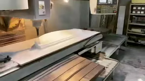 Büyük poliüretan levha, kesim makinesinde şekillendirilmek üzere ilerliyor.