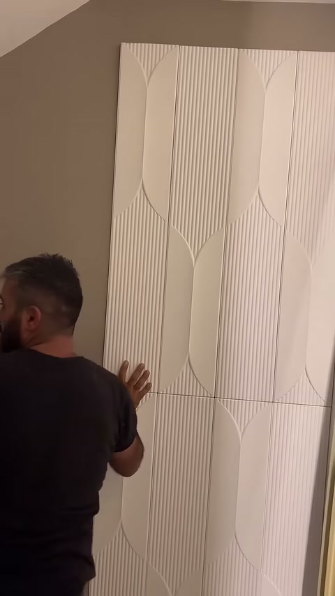 Duvar boyunca uzanan beyaz geometrik panel sıraları kontrol ediliyor.