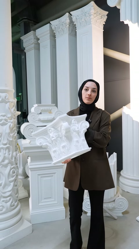 Sunucu sütun başlığı parçasını kameraya doğru tutarak gösteriyor