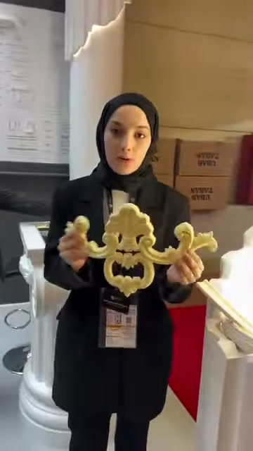 Dekoratif flex parça, stant görevlisinin ellerinde yatay biçimde duruyor