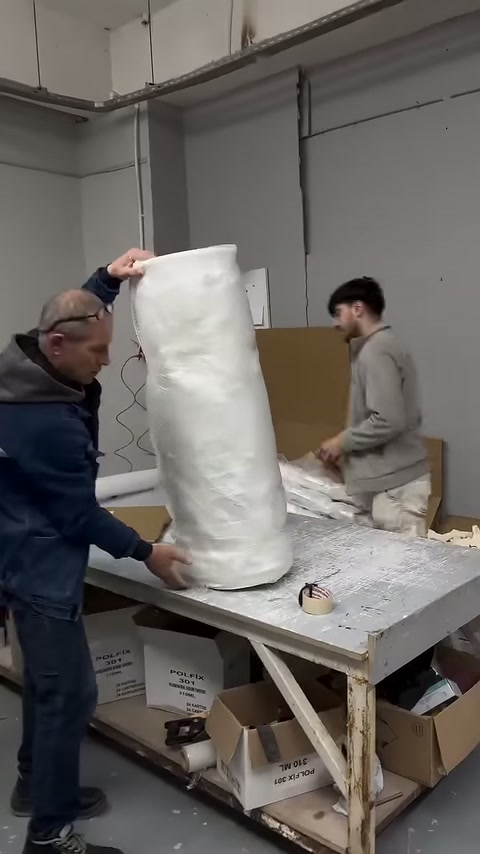 Sütun gövdesinin koruyucu ambalajı iki çalışan tarafından tamamlanıyor