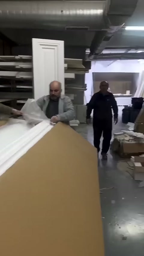 Çalışanlar uzun beyaz profilleri açık kutuda düzenliyor