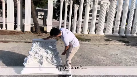 Kabartmalı beyaz sütun başlığı açık alanda elle inceleniyor