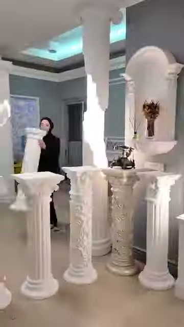İnce ve kalın gövdeli beyaz sehpalar sunucunun önünde diziliyor.