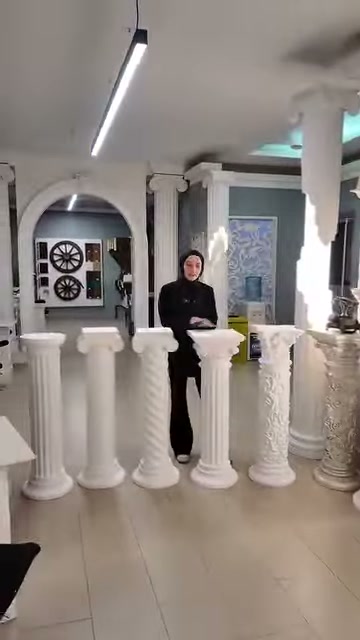 Geniş showroomda sıralanan beyaz kaideler sunucuyla birlikte sergileniyor.