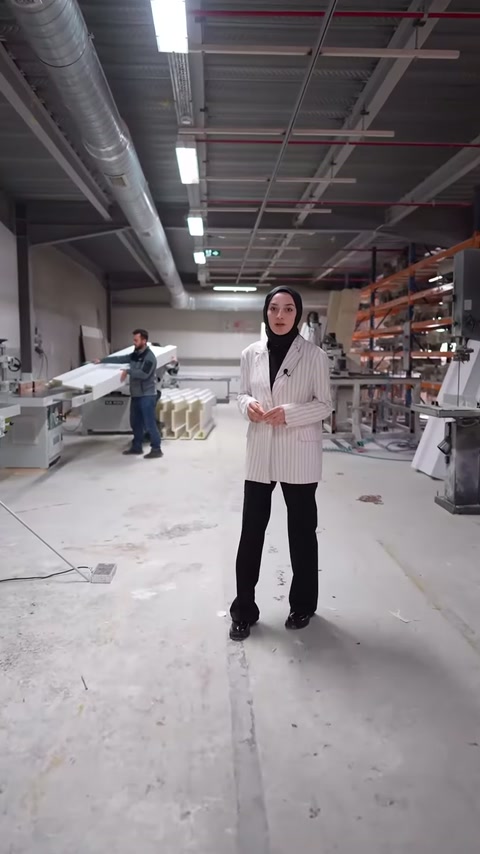 Sunucu, arka plandaki üretim sürecini atölye içinde ayakta anlatıyor.