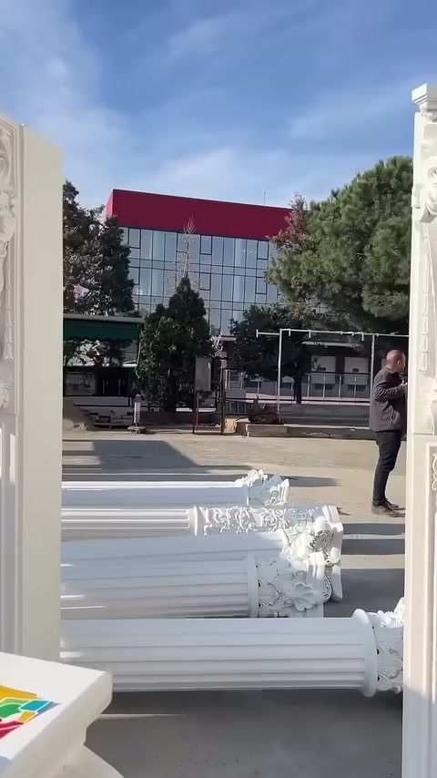 Dikey beyaz sütun detayı ve yerde istiflenmiş gövdeler görülüyor