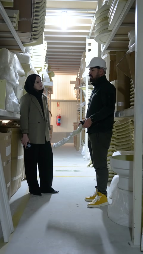 Üretici raflar arasındaki dekoratif elemanları eliyle işaret ediyor