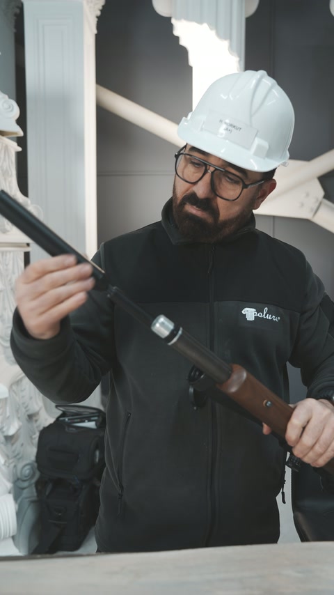 Baretli çalışan tüfeğin namlusunu göz hizasında kontrol ediyor.