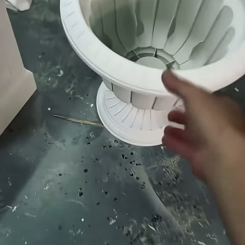 Usta eli, beyaz dekoratif saksının geniş üst kenarını kontrol ediyor.