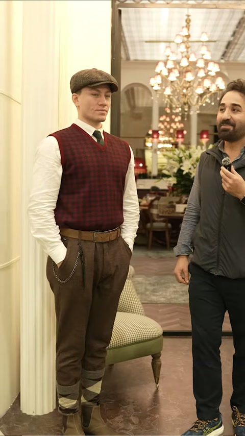 Beyaz sütunlu geçitte klasik koltuk ve kristal avize sergileniyor
