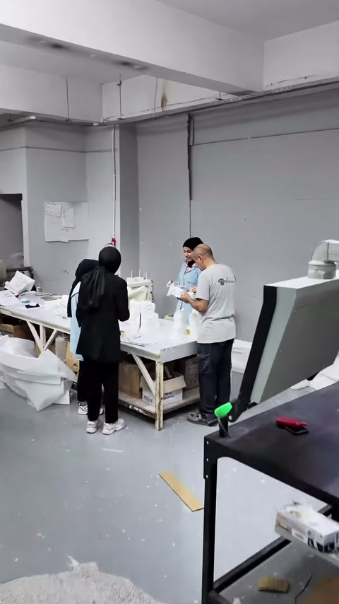 Çalışanlar beyaz dekoratif parçaları tezgâhta işlerken sunucu süreci inceliyor.