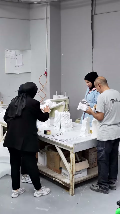 Sunucu tezgâhtaki beyaz parçayı incelerken çalışanlar üretime devam ediyor.