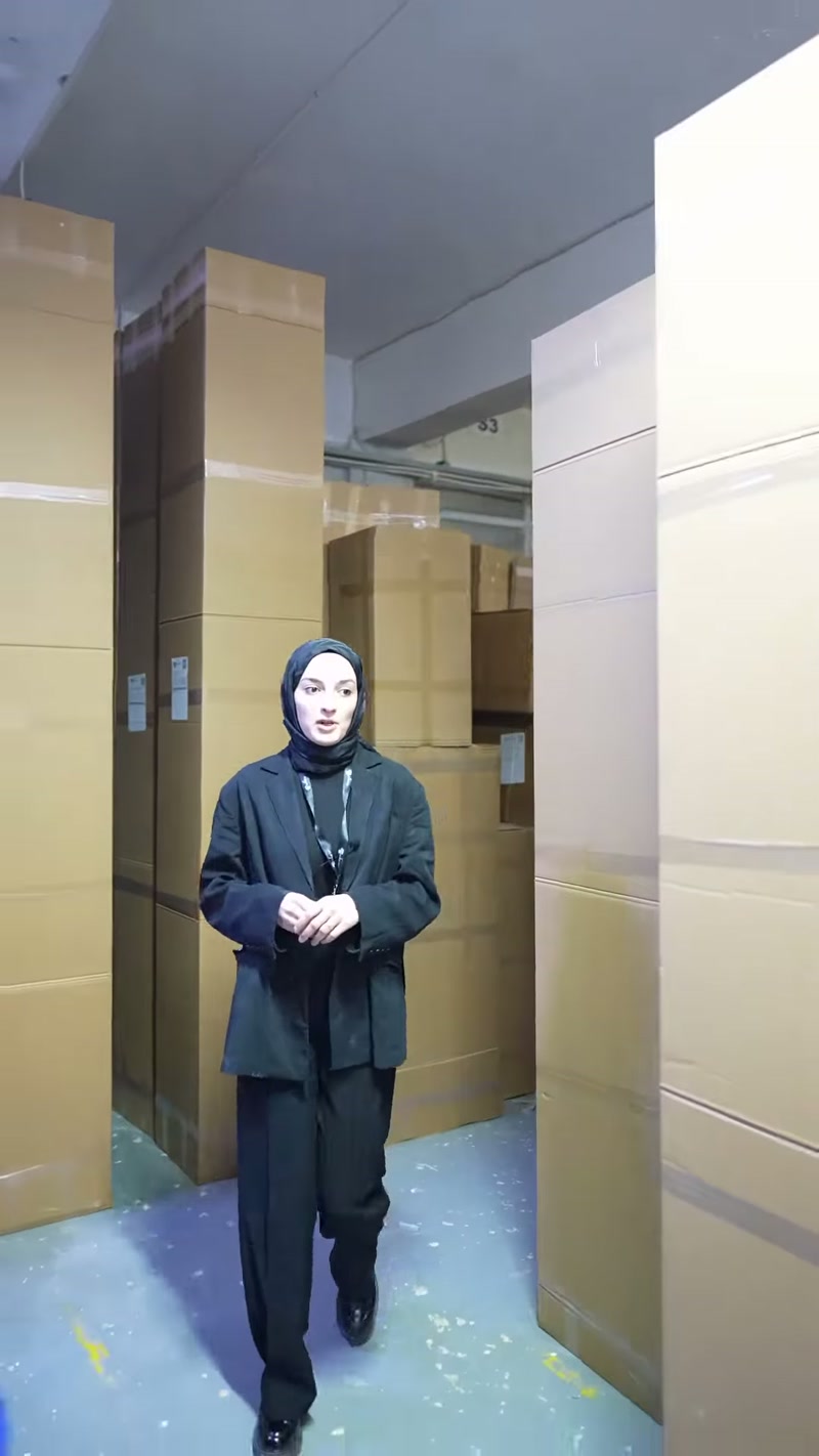 Fabrika deposundaki kutu sıraları arasında ürün hazırlığı anlatılıyor.
