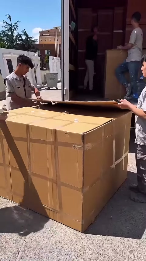 Ambalaj kapağı kaldırılırken diğer çalışan koliyi sabit tutuyor
