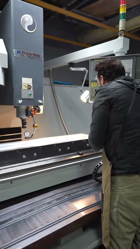 Üretim çalışanı uzun oluklu paneli makine tablasında denetliyor