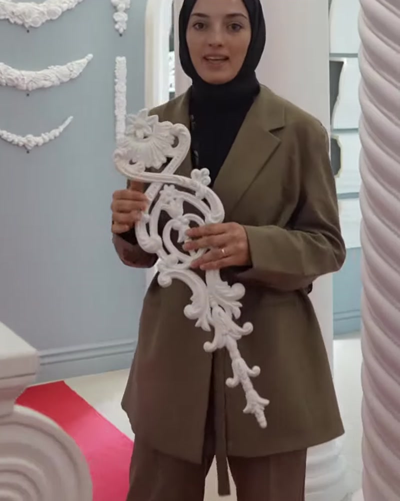 Sunucu, uzun beyaz poliüretan motif örneğini iki eliyle sergiliyor