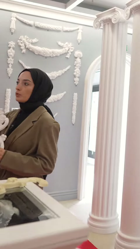 Sunucu elindeki uzun motifle sütunlu teşhir alanında konuşuyor