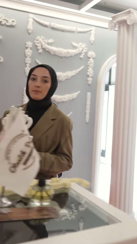 Dekoratif motif, masa ve bayrakların arkasında sunucunun elinde görülüyor