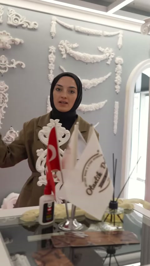 Sunucu beyaz kıvrımlı süslemeyi masa başında dikey biçimde sergiliyor