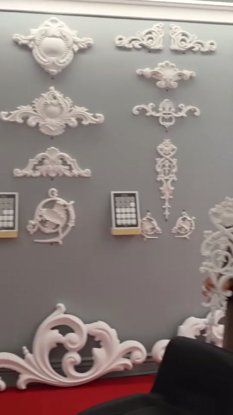 Kabartmalı süsleme modelleri gri duvar ve kırmızı zeminde sergileniyor