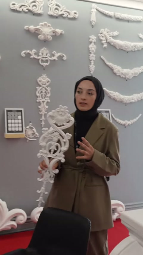Sunucu uzun beyaz motifi duvar koleksiyonunun önünde tanıtıyor