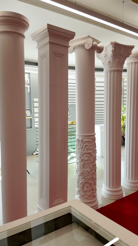 Kare kaideli pembe ve beyaz dekoratif sütunlar showroom alanını bölümlüyor.